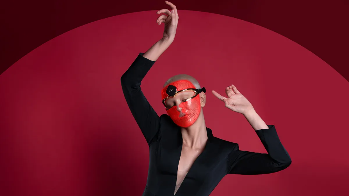 A woman dancing with a red light therapy mask